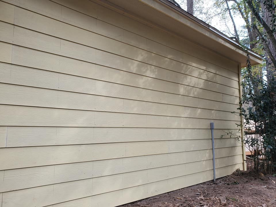Yellow siding on a building with a brown roof and gutter.