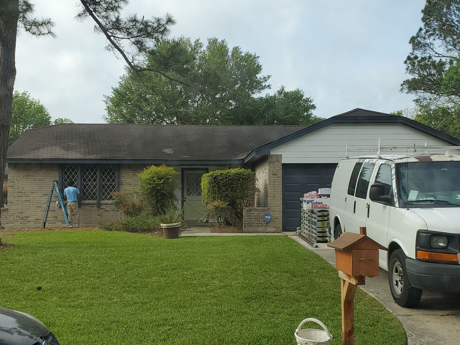 A residential house with a white van parked in front. A person is working on the house.