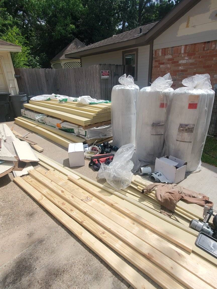 Construction materials, including insulation and lumber, are staged outside a building, ready for use.