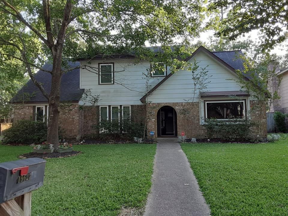 Two-story house with brick and siding, a pathway to the front door, and a mailbox in front.