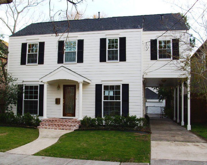 White two-story house with black shutters, brick steps, and a driveway carport.