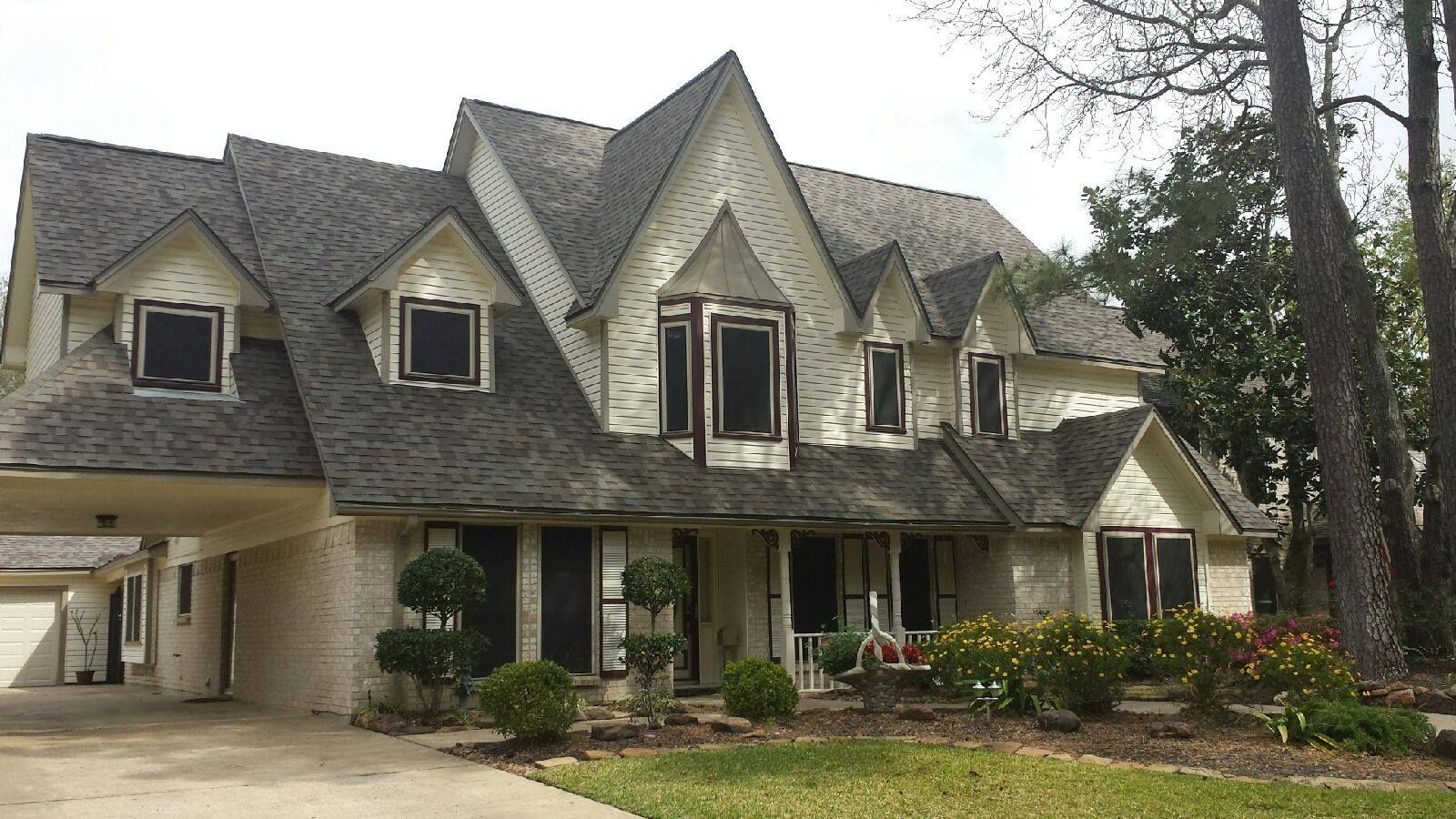 Large, multi-story house with a steeply pitched roof, pale yellow exterior, and several windows.