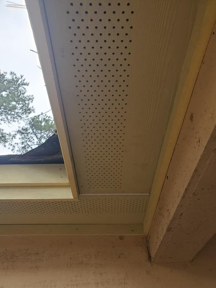 Beige soffit with ventilation holes, installed on a building's underside near the roof.