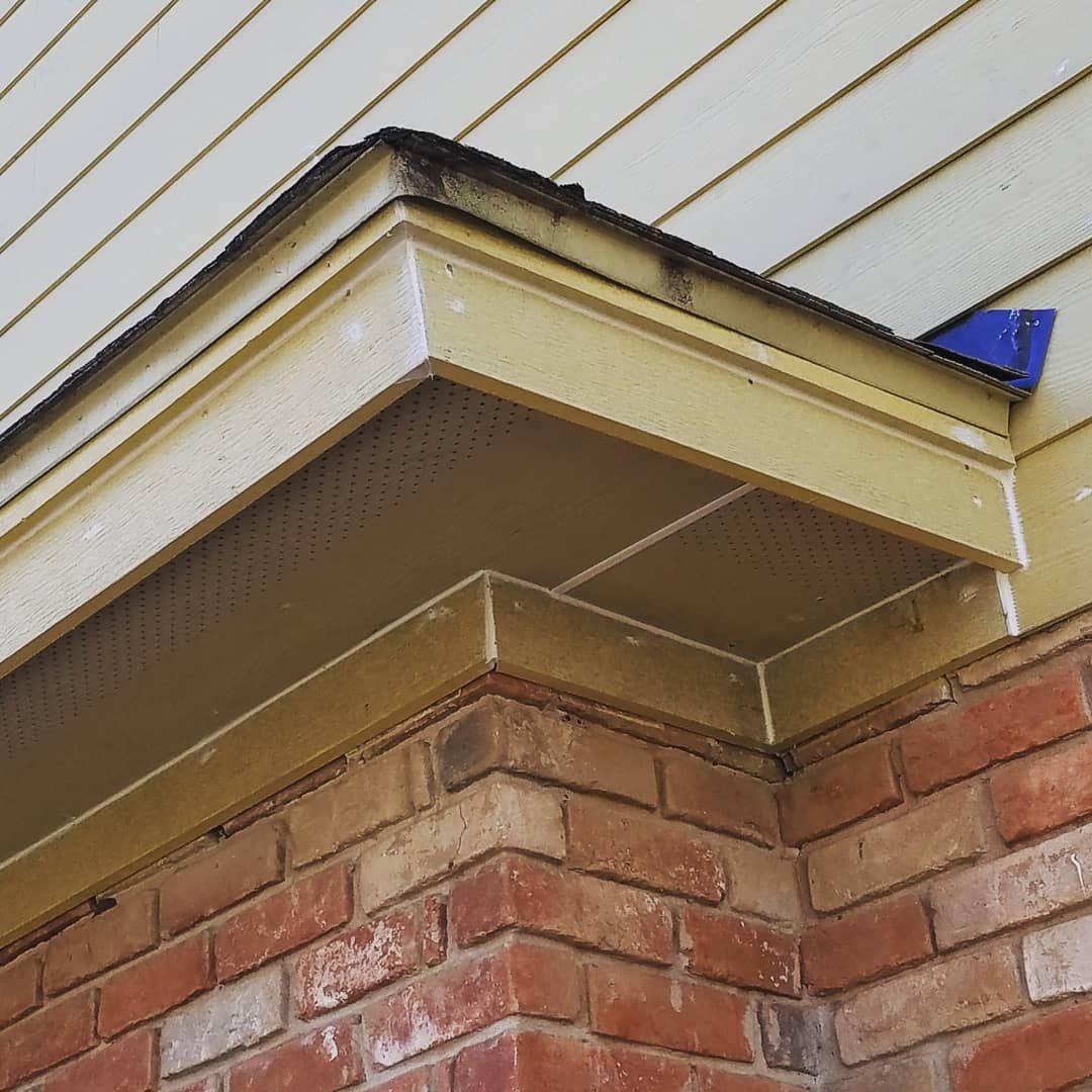 Brick corner of building with yellow trim and siding.
