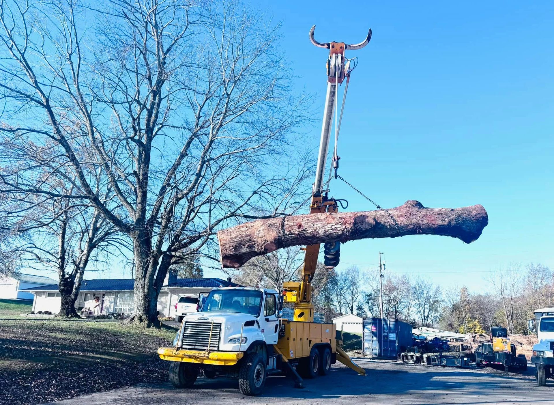 A large log is being lifted by a crane on top of a truck.