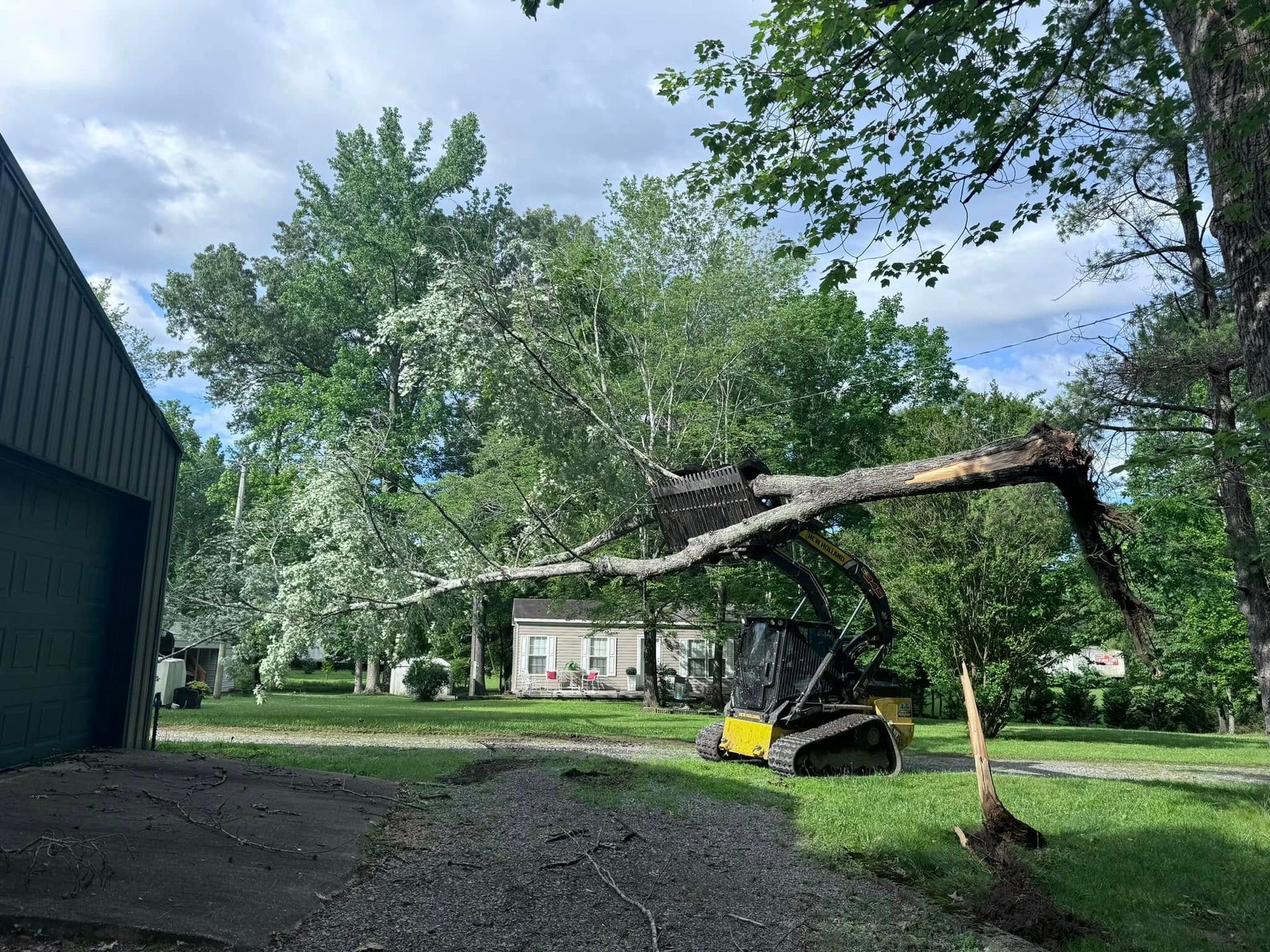 A bulldozer is cutting down a tree in a yard.