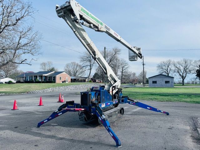 A blue and white crane is parked in a parking lot.