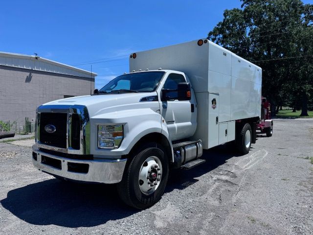 A white truck with a box on the back is parked in a parking lot.