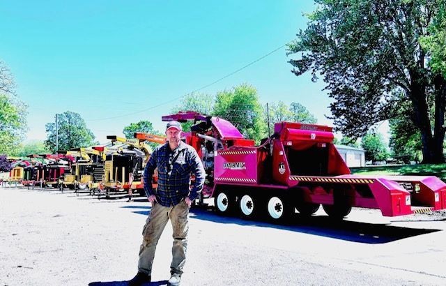 A man is standing in front of a large red truck