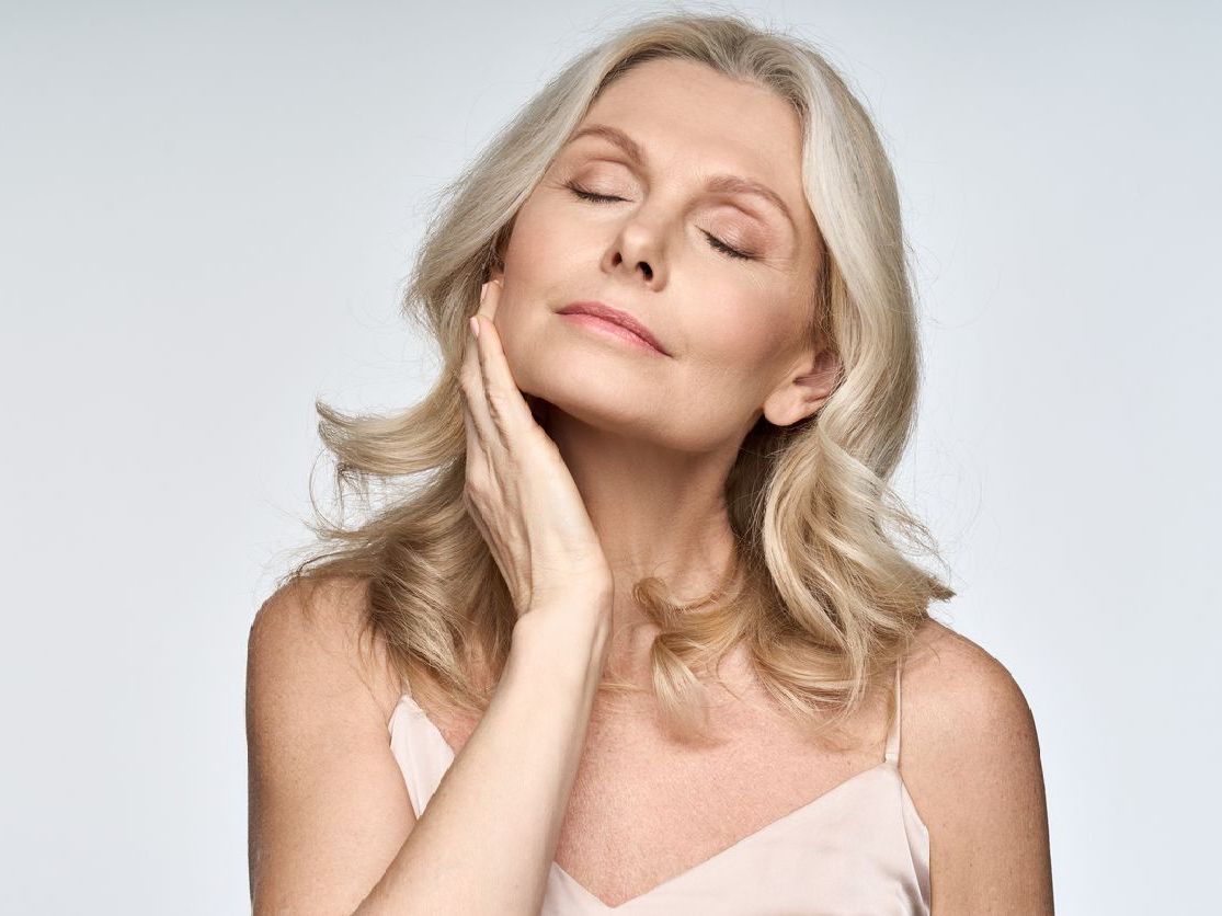 A woman is touching her face with her hand and her eyes closed.