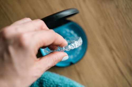 A person is holding a clear retainer in their hand.