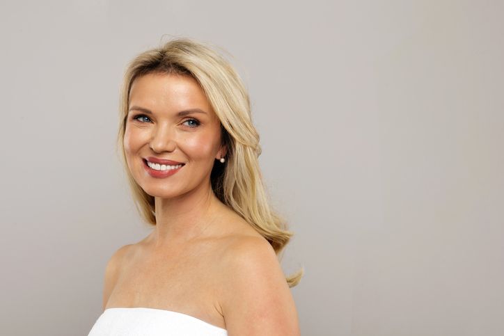 A woman with curly hair is smiling and laughing.