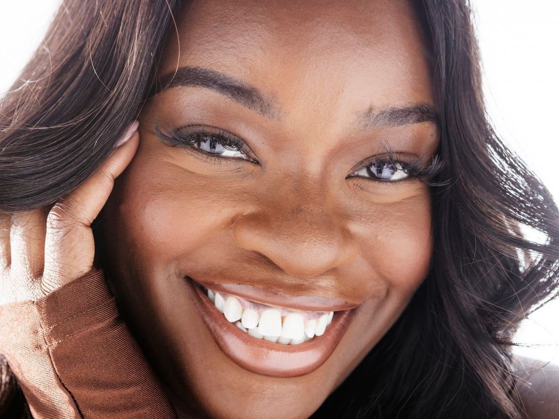 A woman wearing a brown scarf smiles for the camera