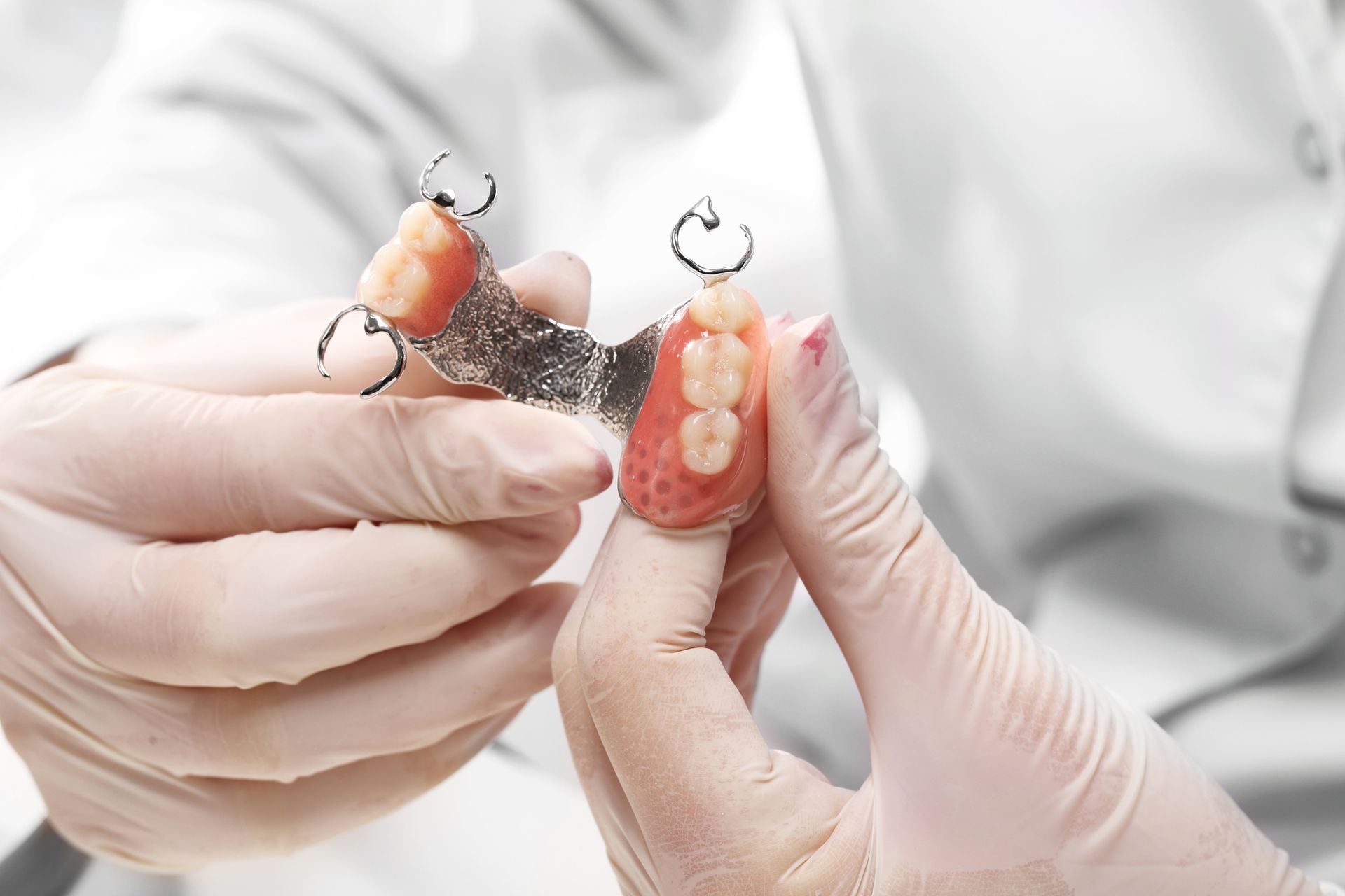 A dentist is holding a denture in his hands.