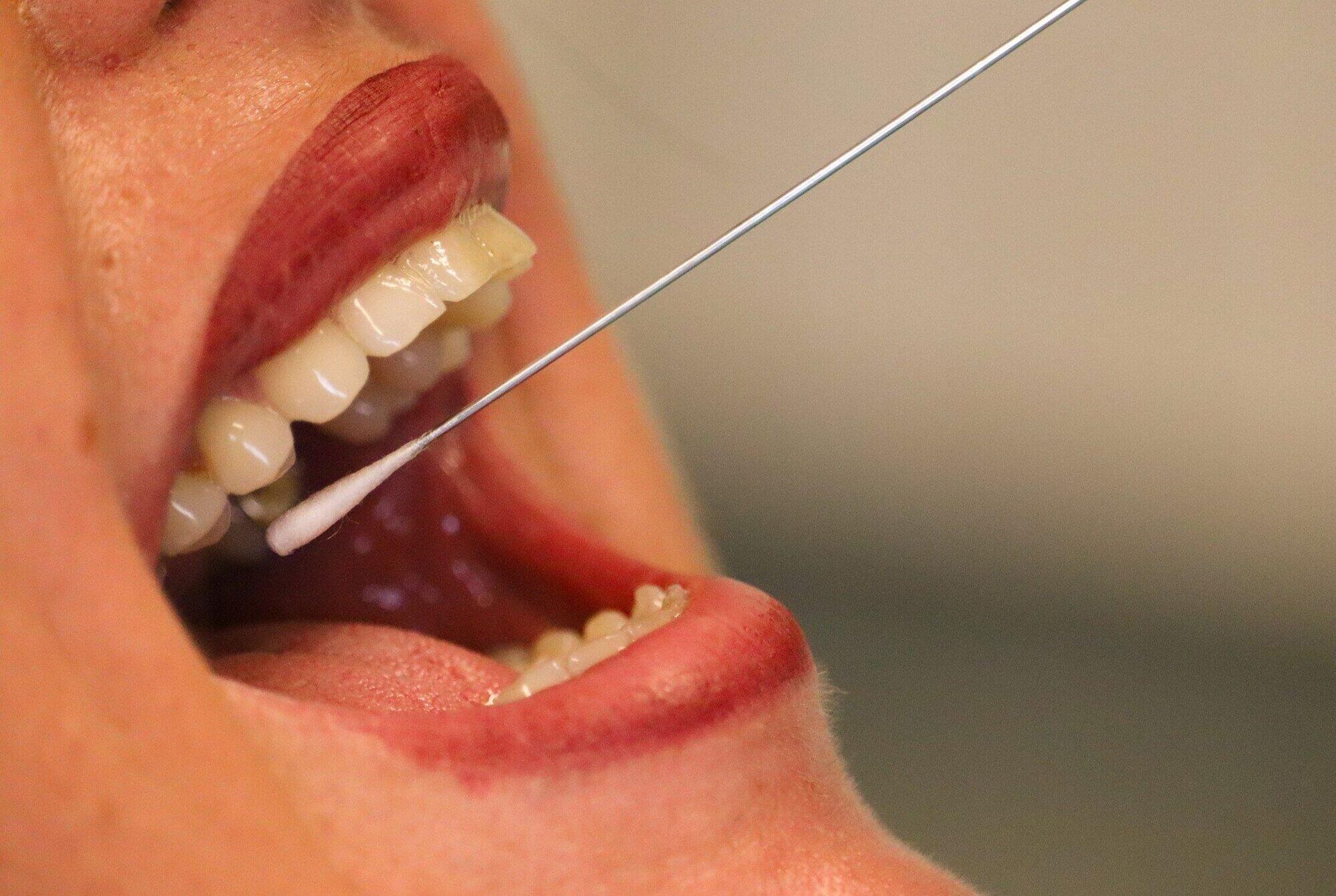 A woman is taking a sample from her mouth with a swab.