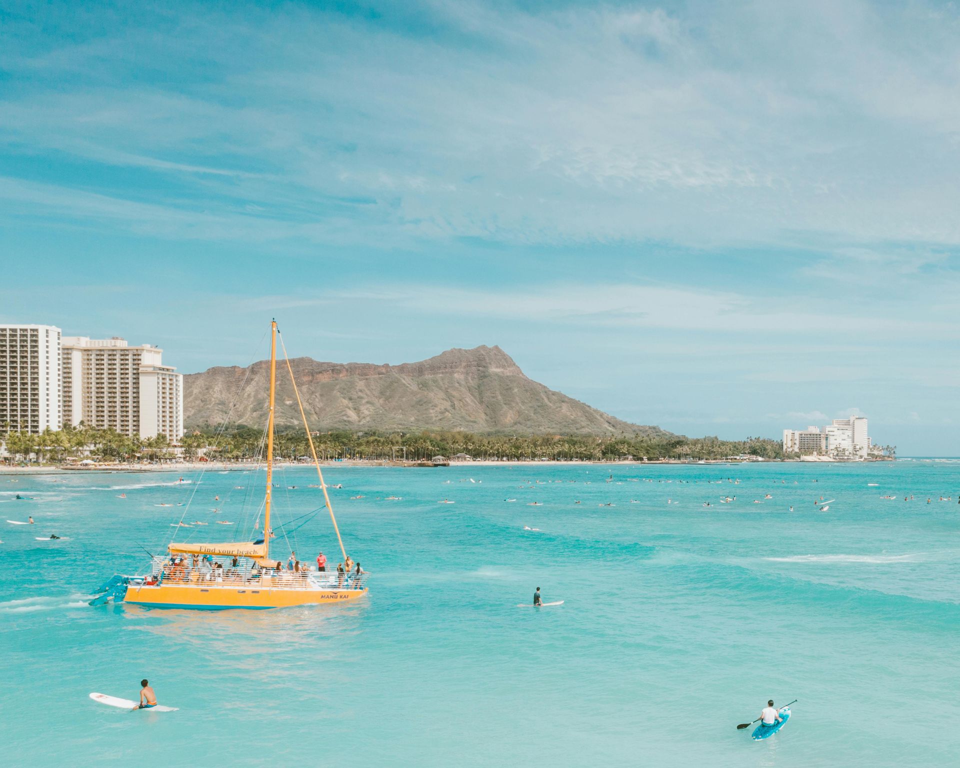 A yellow sailboat is floating on top of a large body of water.