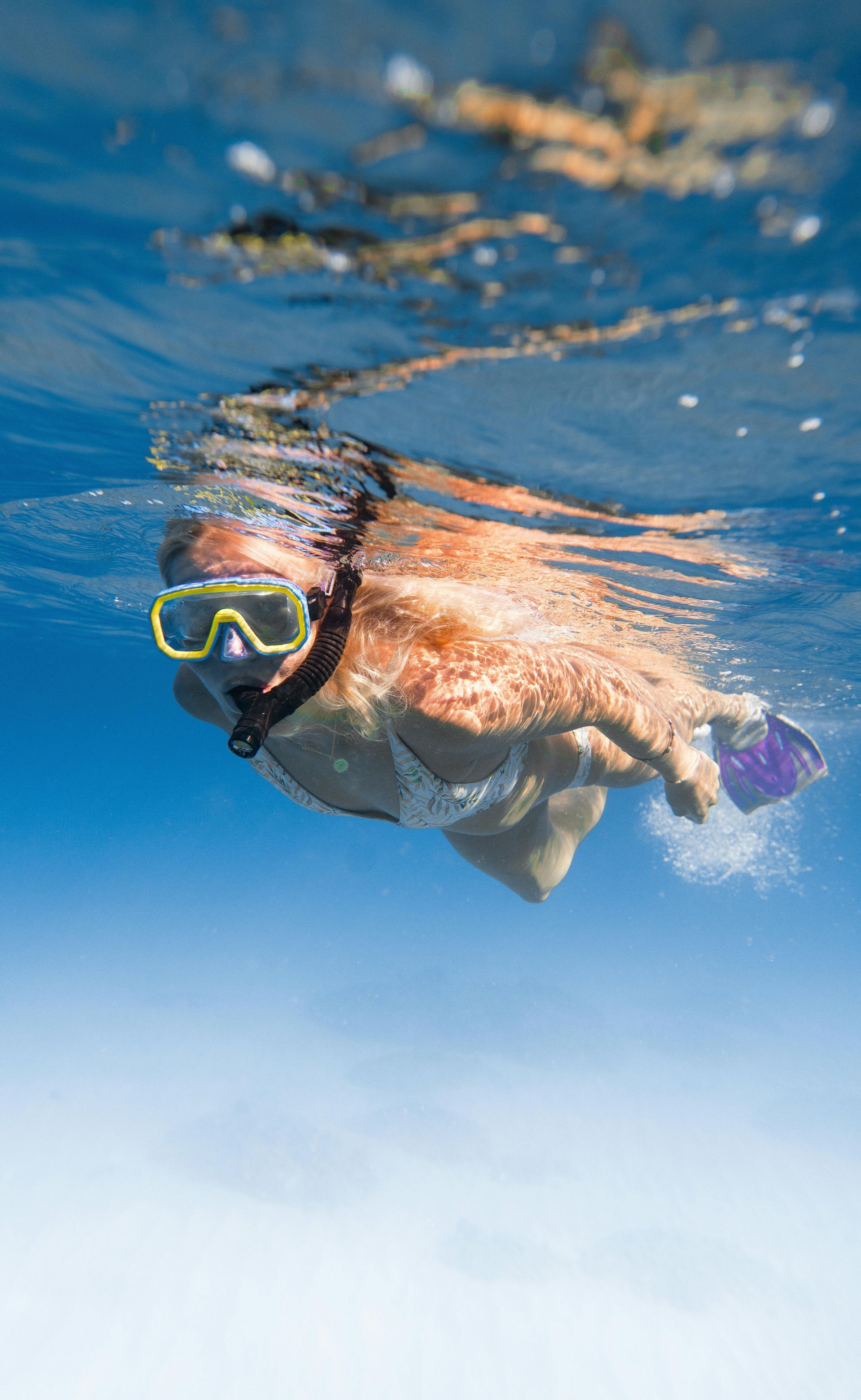 A woman is swimming underwater in the ocean wearing a mask and flippers.