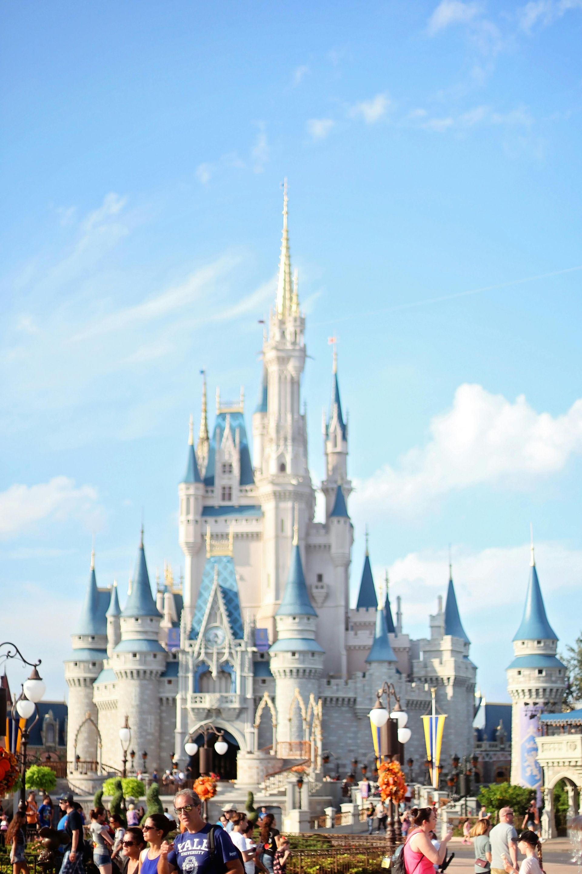 A group of people are walking in front of a large castle at disney world.