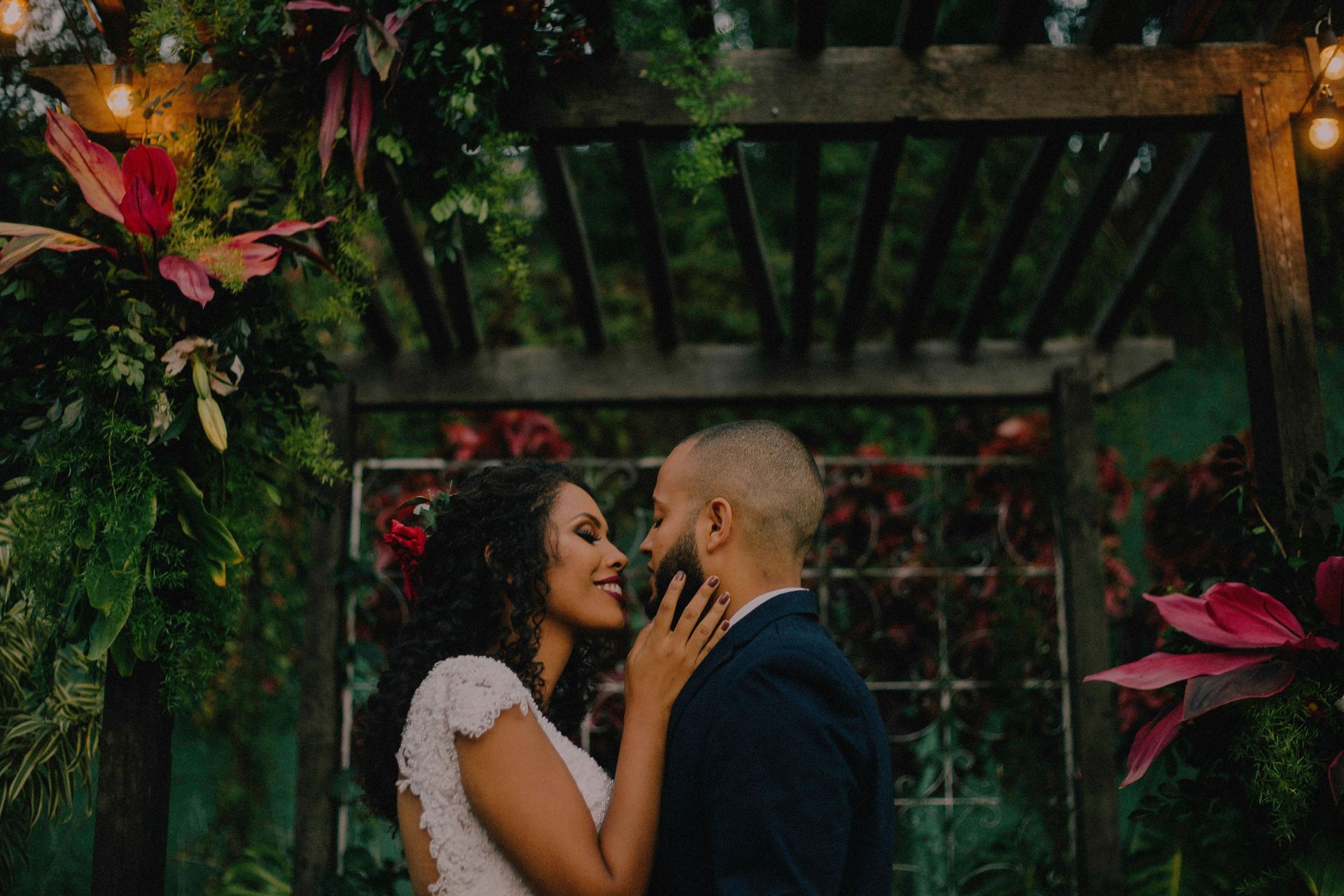 A bride and groom are kissing under a pergola.