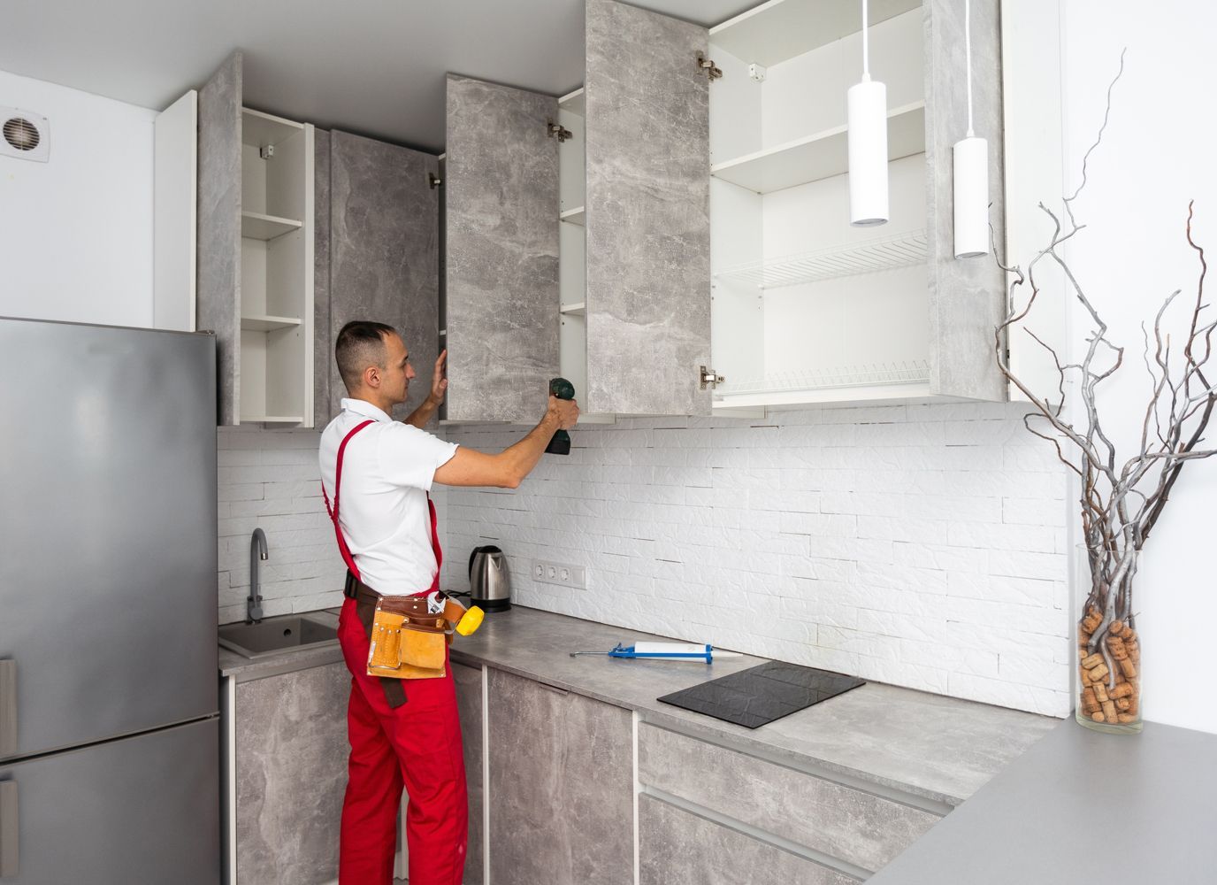 A man is installing cabinets in a kitchen.