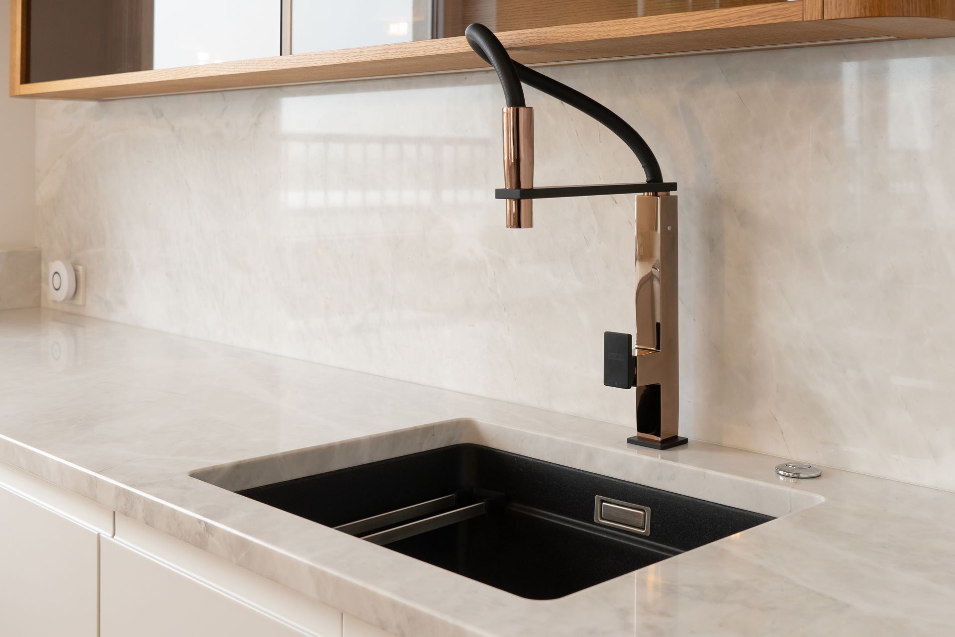 A kitchen sink with a copper faucet and a black sink.
