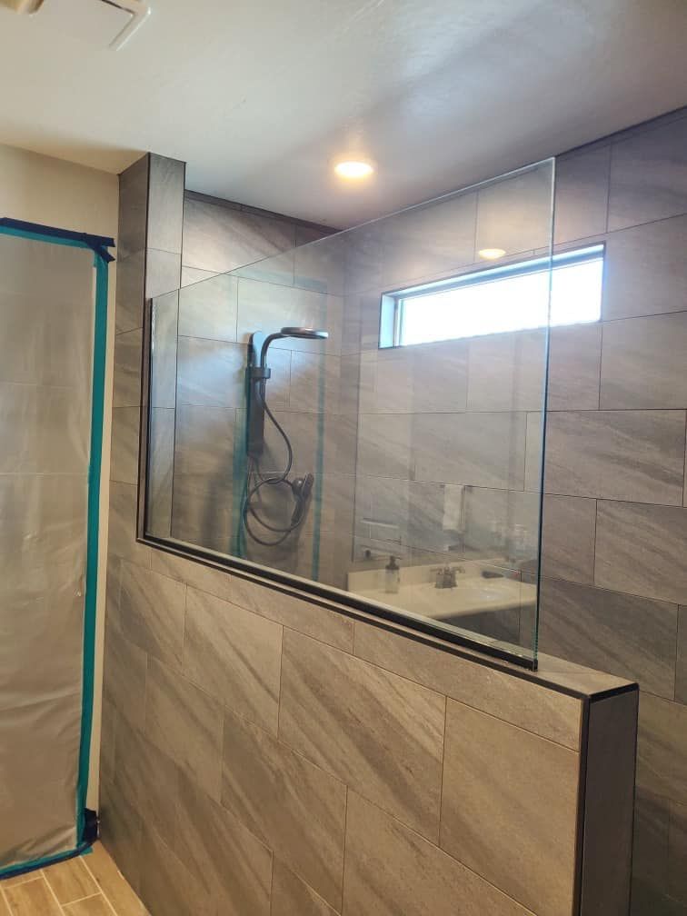 A bathroom with a glass shower door and a window.