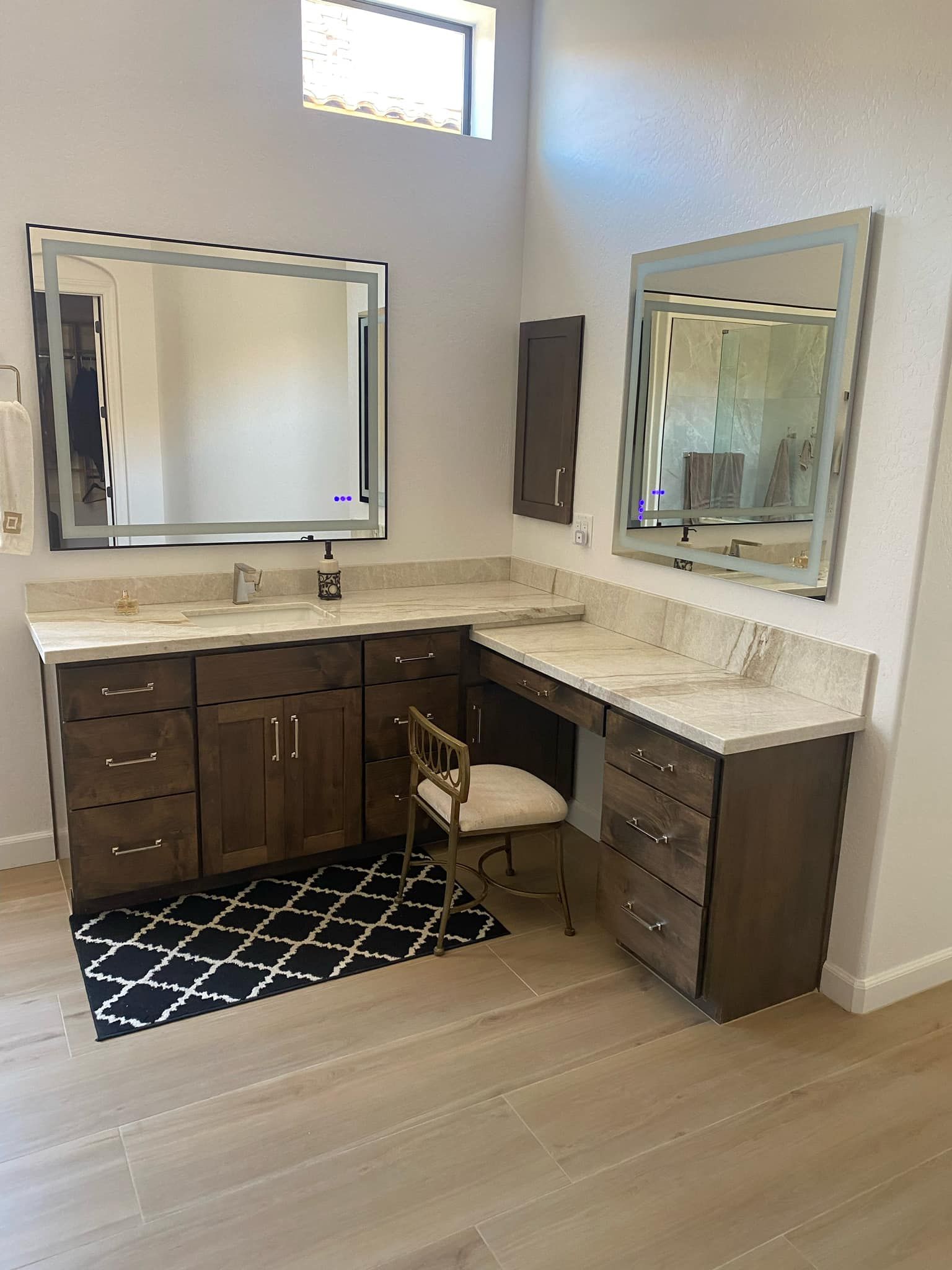 A bathroom with two sinks , two mirrors , a desk and a chair.