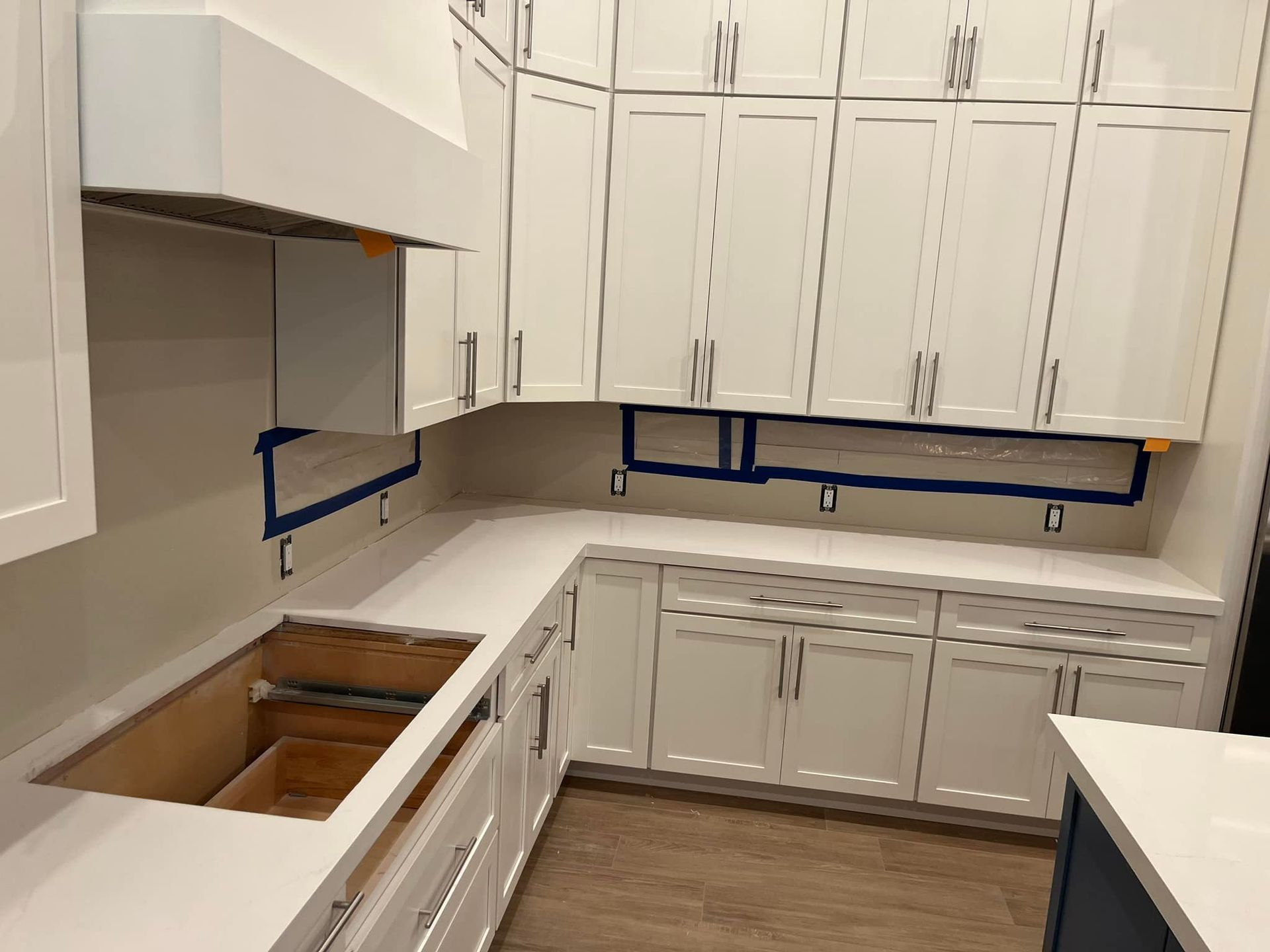 A kitchen with white cabinets and white counter tops is being remodeled.