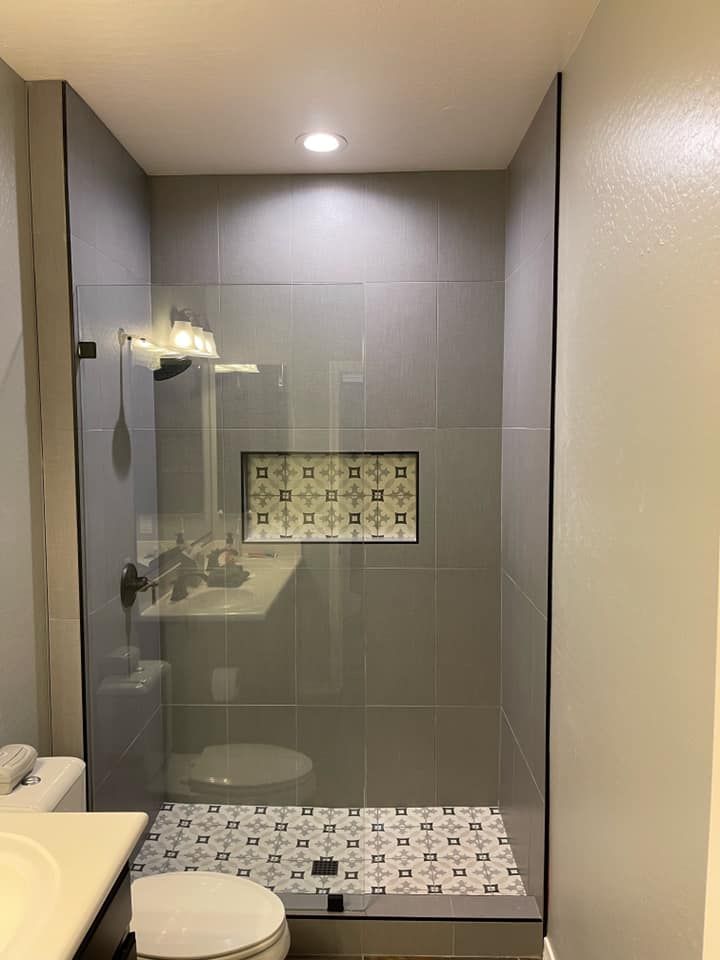 A bathroom with a walk in shower , toilet , sink and mirror.