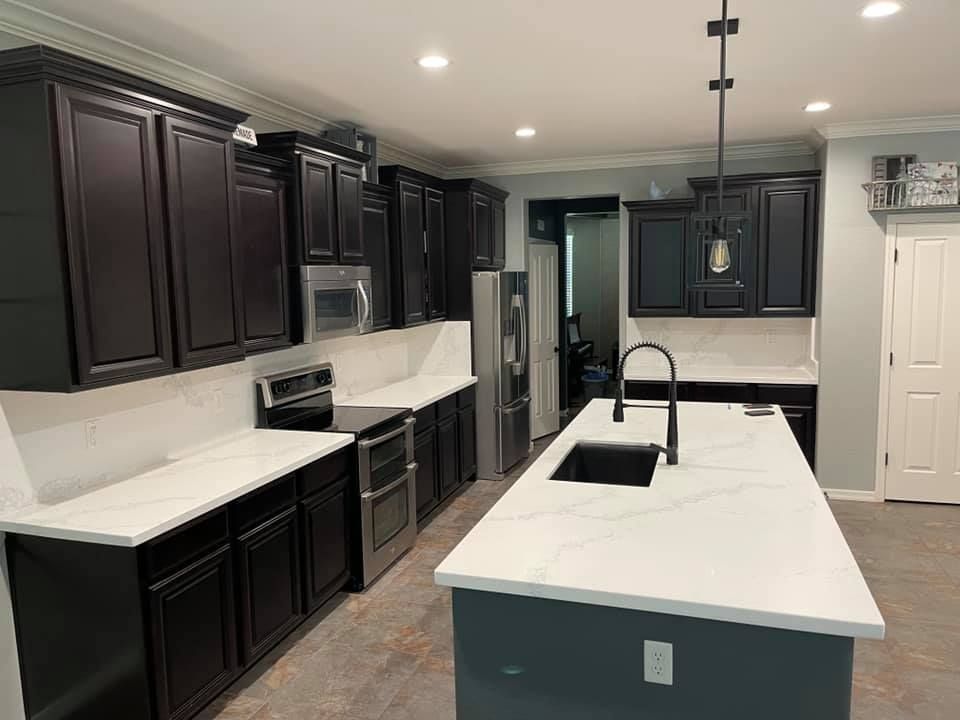 A kitchen with black cabinets and white counter tops and a large island.