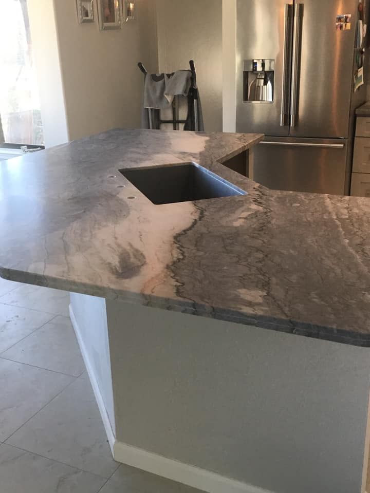 A kitchen with a marble counter top and a sink
