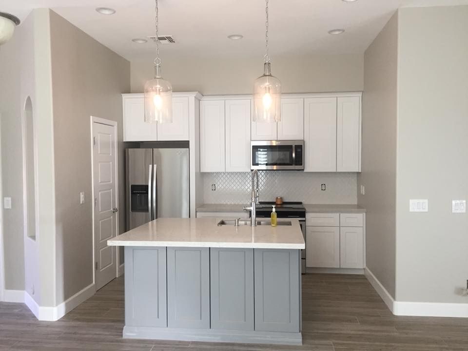 A kitchen with white cabinets , stainless steel appliances , and a large island.