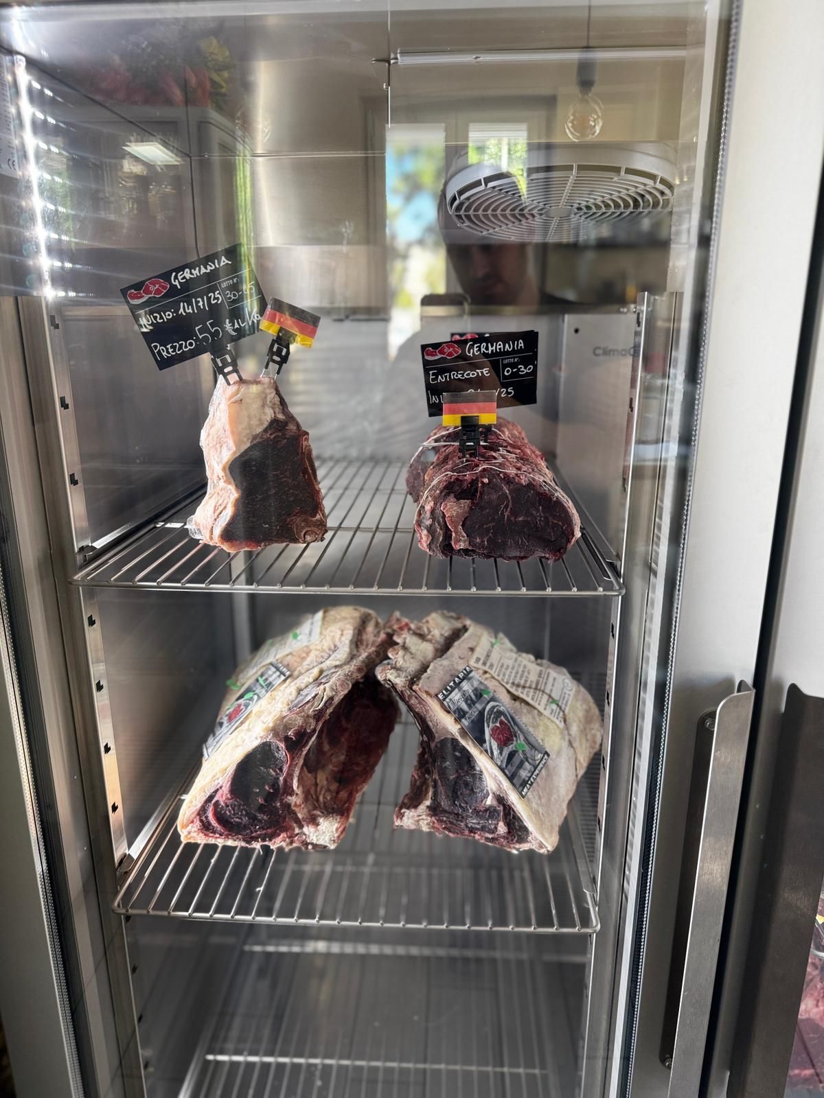 Vetrina per la carne contenente diversi grandi tagli di manzo frollato a secco, illuminata da luci interne.