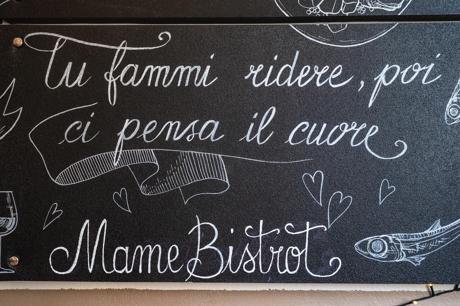Insegna per Mame Bistro con calligrafia bianca su sfondo nero: