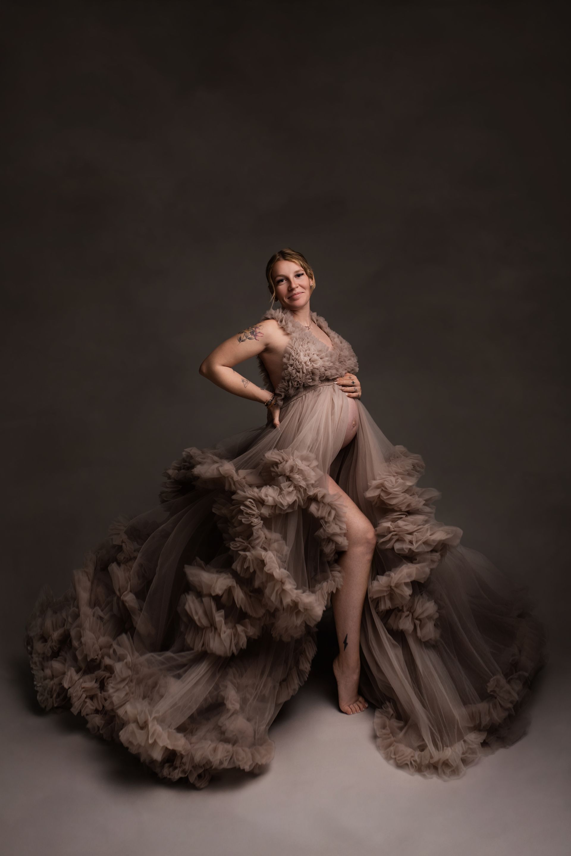 Une femme enceinte dans une longue robe violette tient son ventre.