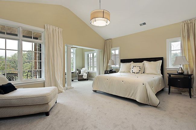 a masters bedroom with white bed cover