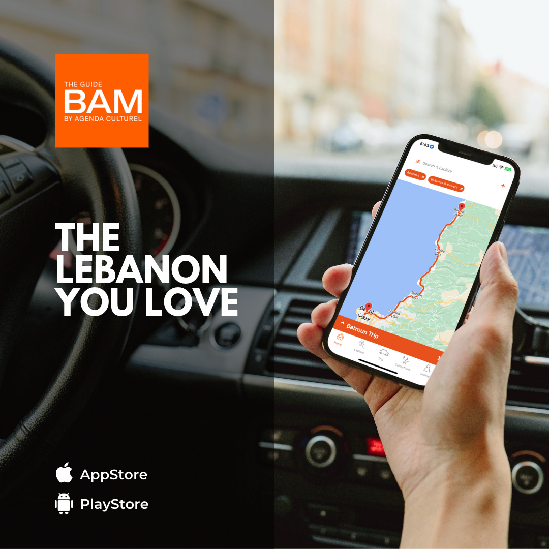 A person is holding a cell phone in their hand in front of a car.