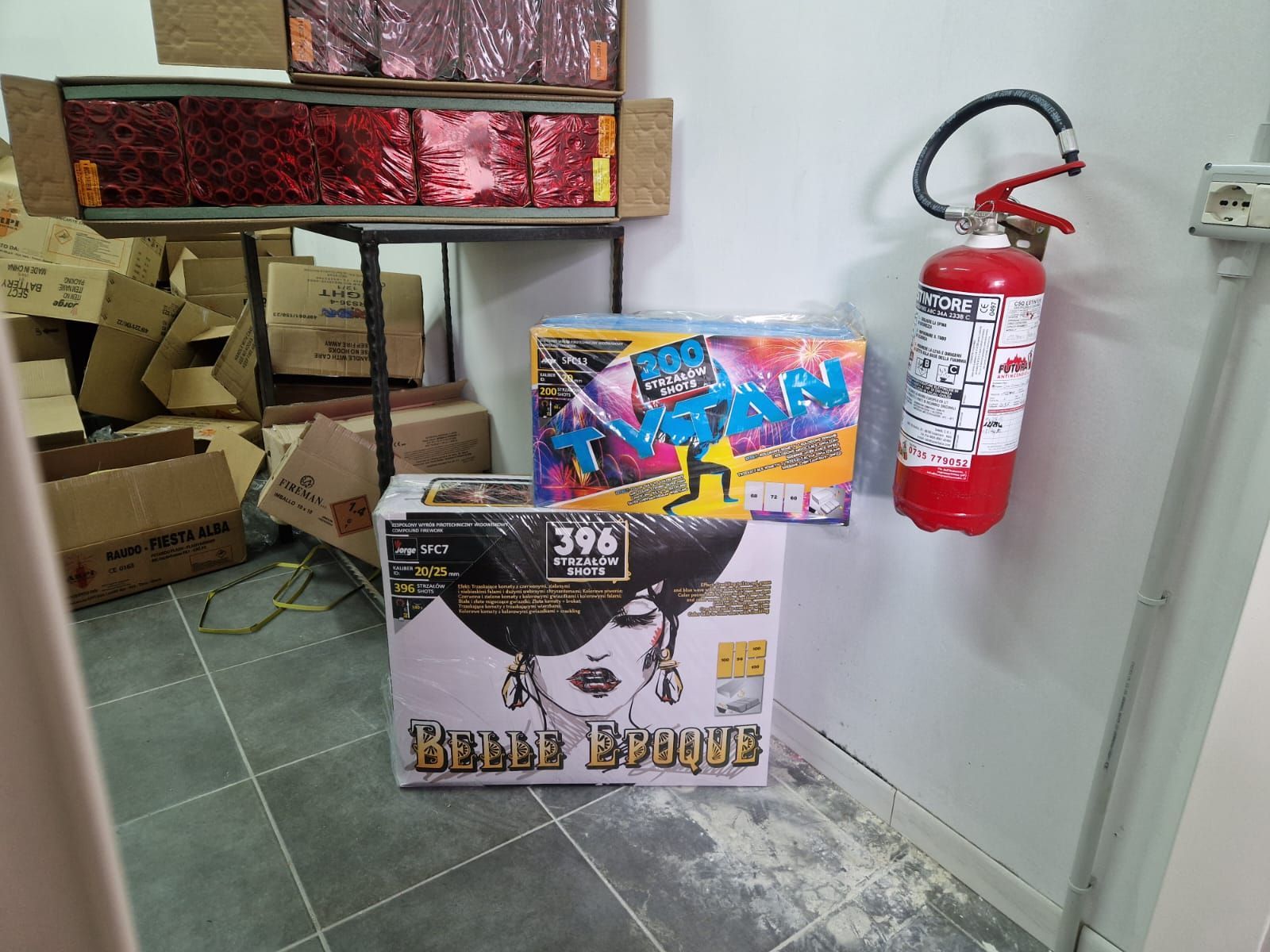 Un estintore è appeso a una parete accanto a una scatola di fuochi d'artificio.