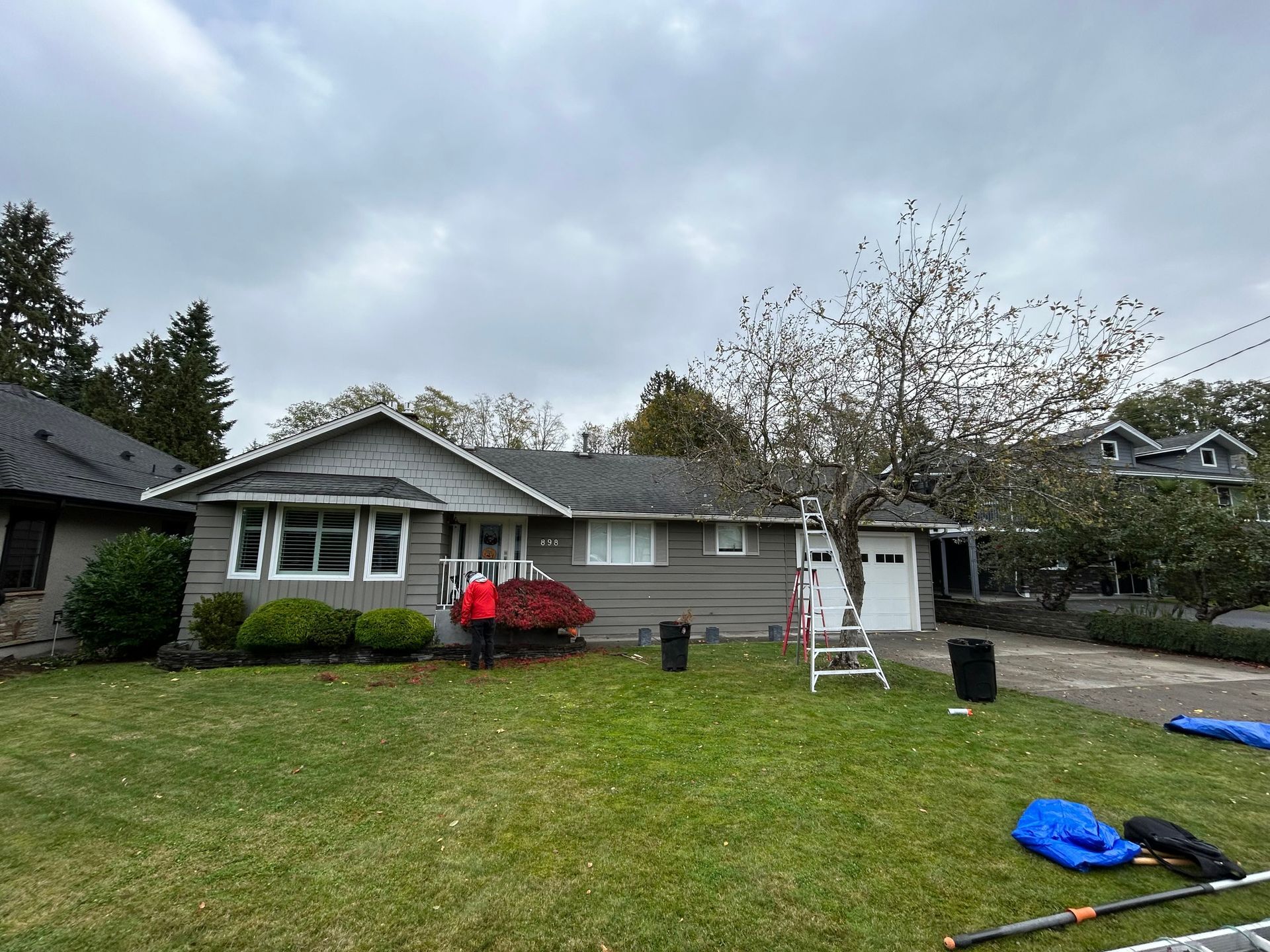 employee working on trimming shrubs in the front yard.