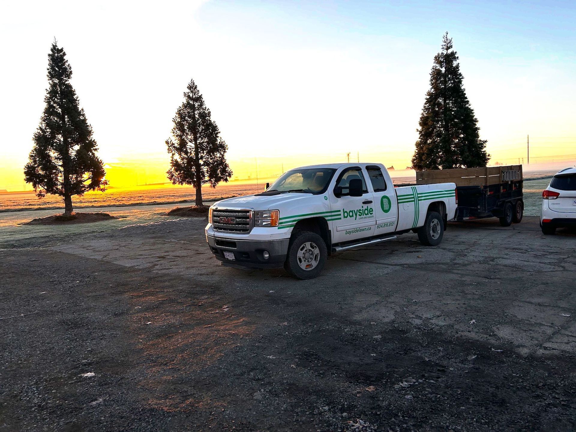 A white truck is parked in a parking lot with trees in the background.