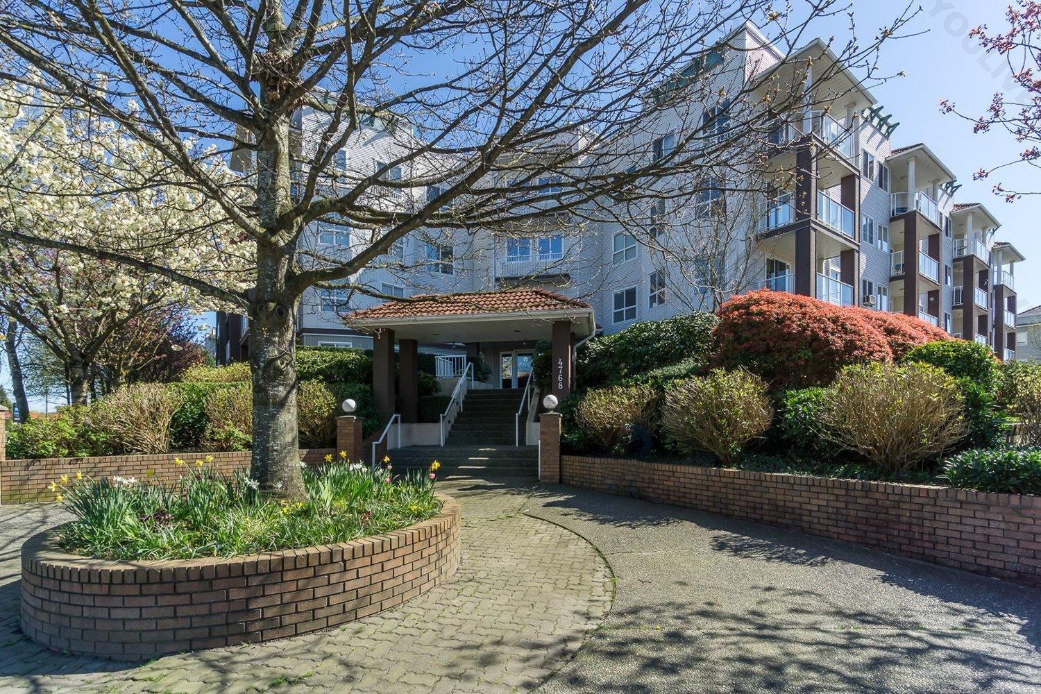 A large apartment building with a tree in front of it.