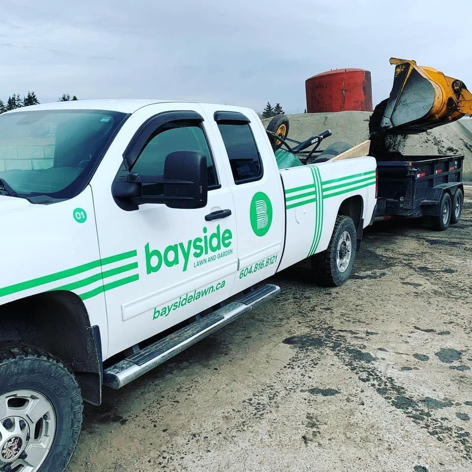 A white and green bayside truck is parked in the dirt