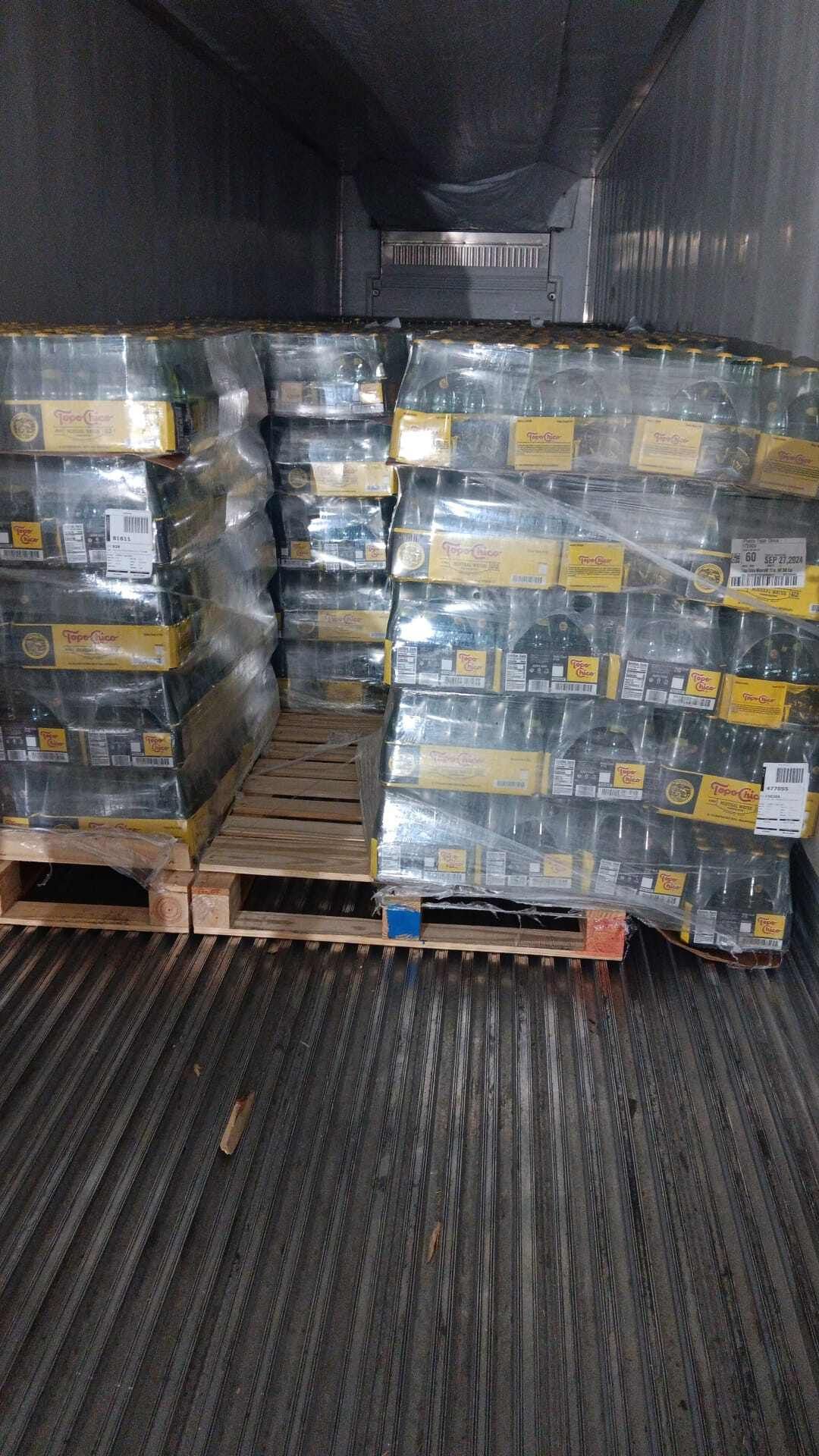 Pallets of bottled product, shrink-wrapped, stacked inside a refrigerated truck.