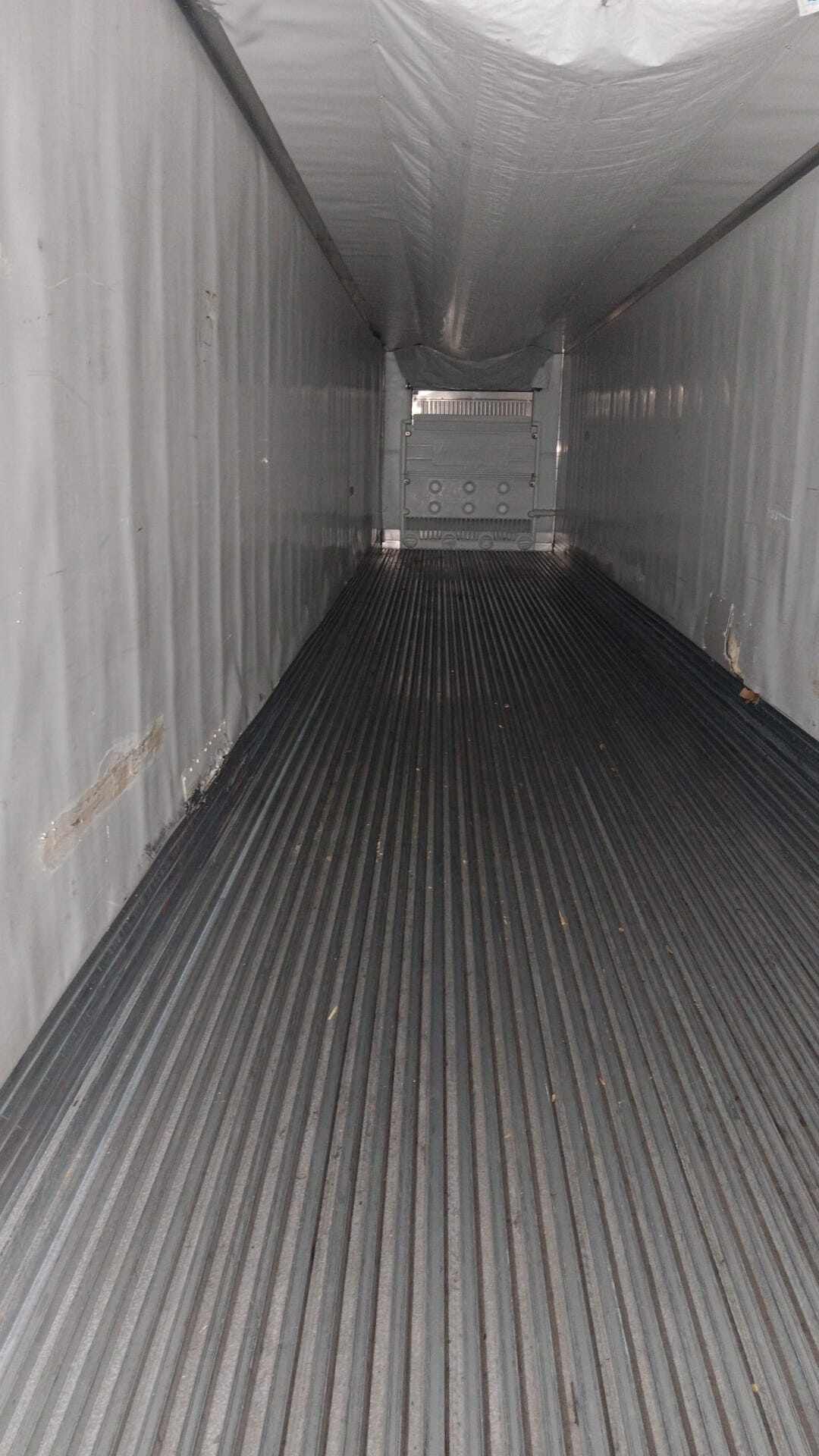 Interior of an empty refrigerated semi-truck trailer with ribbed metal floor, white walls, and ceiling.