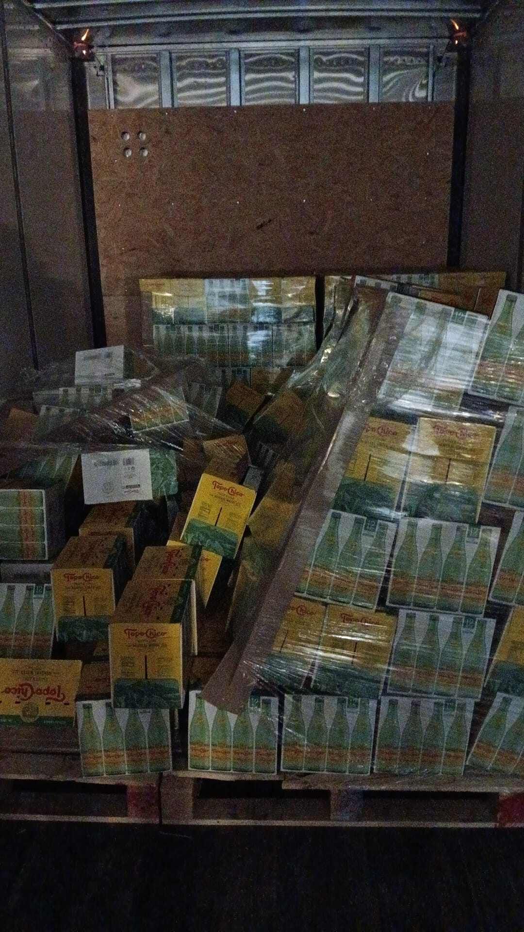 Boxes of product on pallets in a truck, some fallen, partially wrapped in plastic.