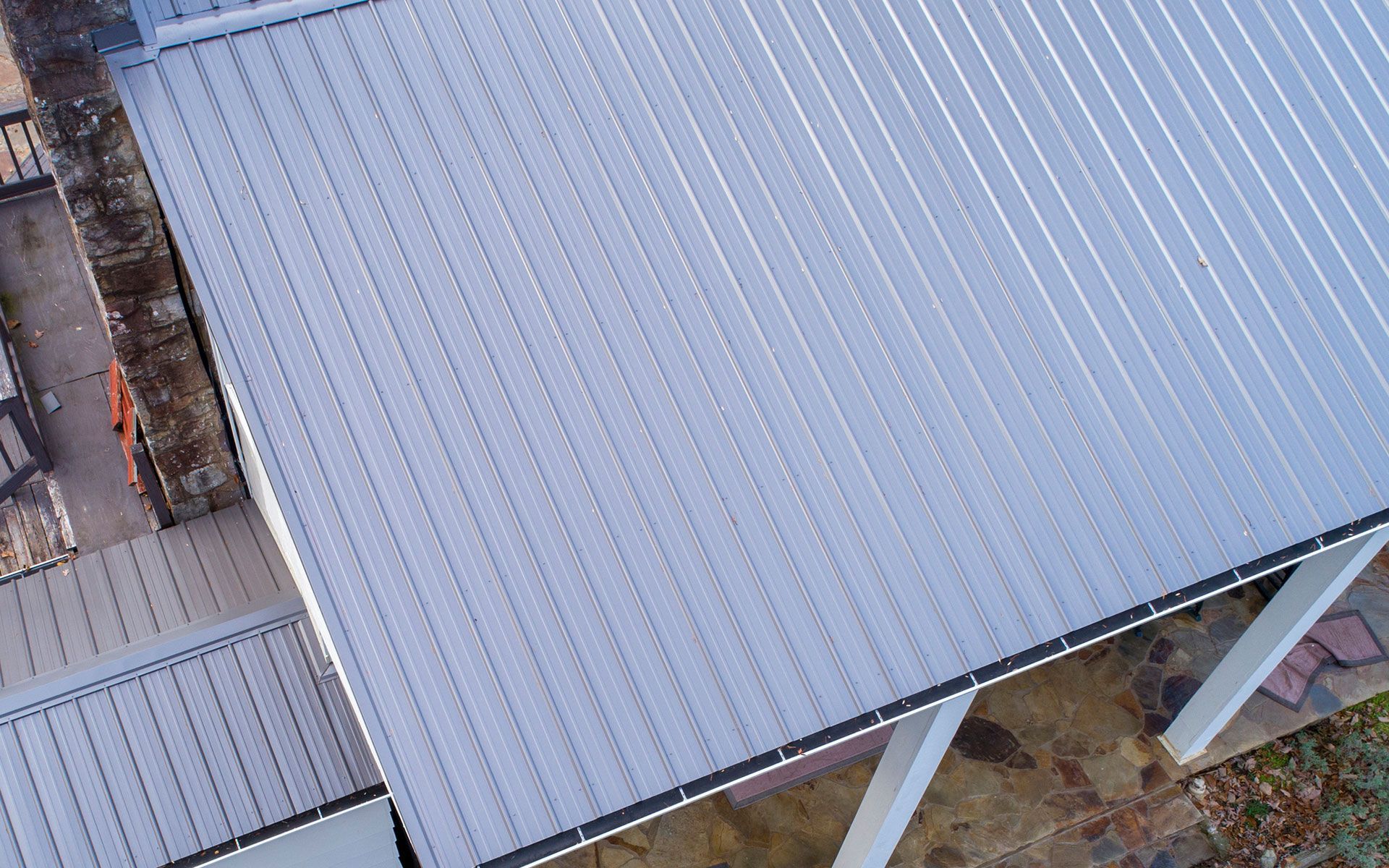 An aerial view of a house with a metal roof and a porch.
