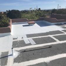 A roof with a white coating on it is being painted.