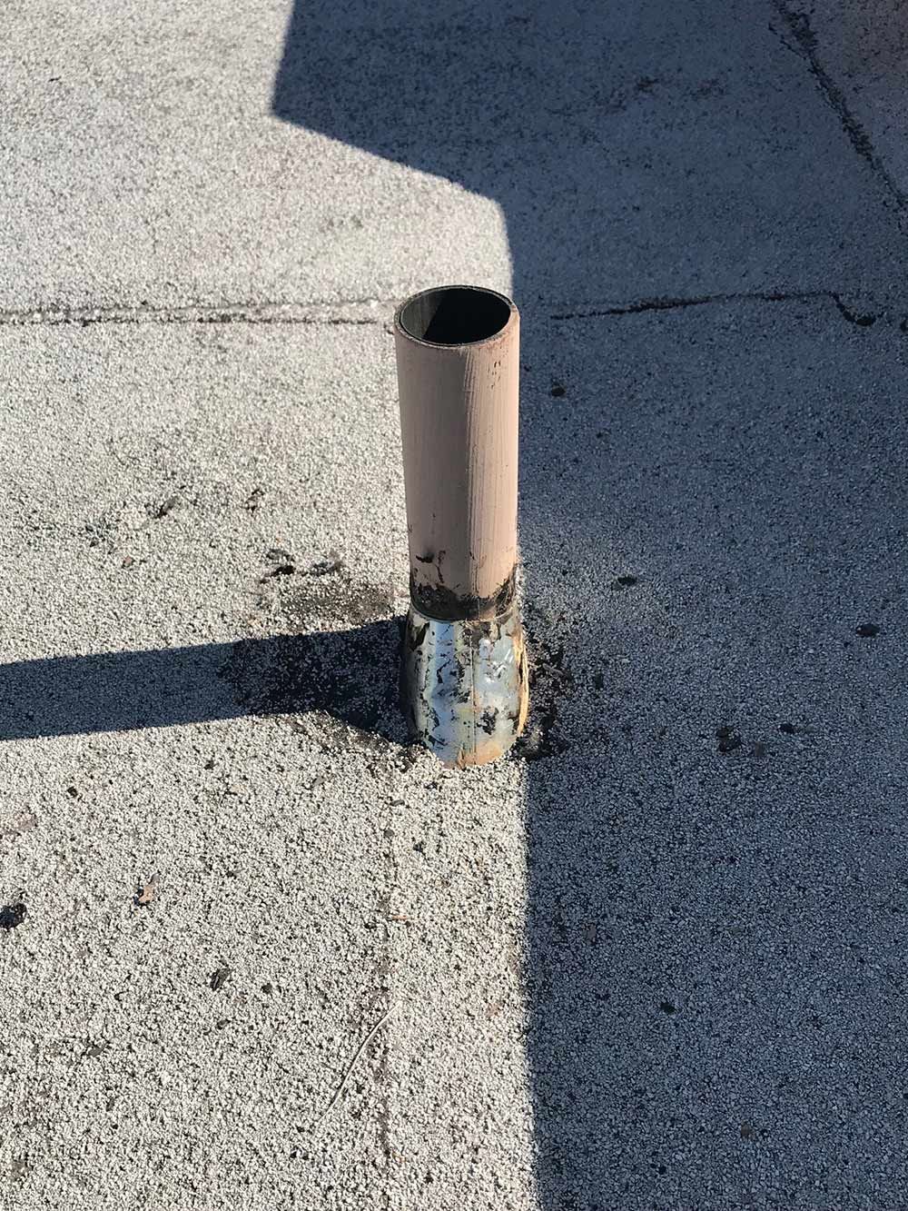 A metal pipe is sitting on top of a concrete surface.