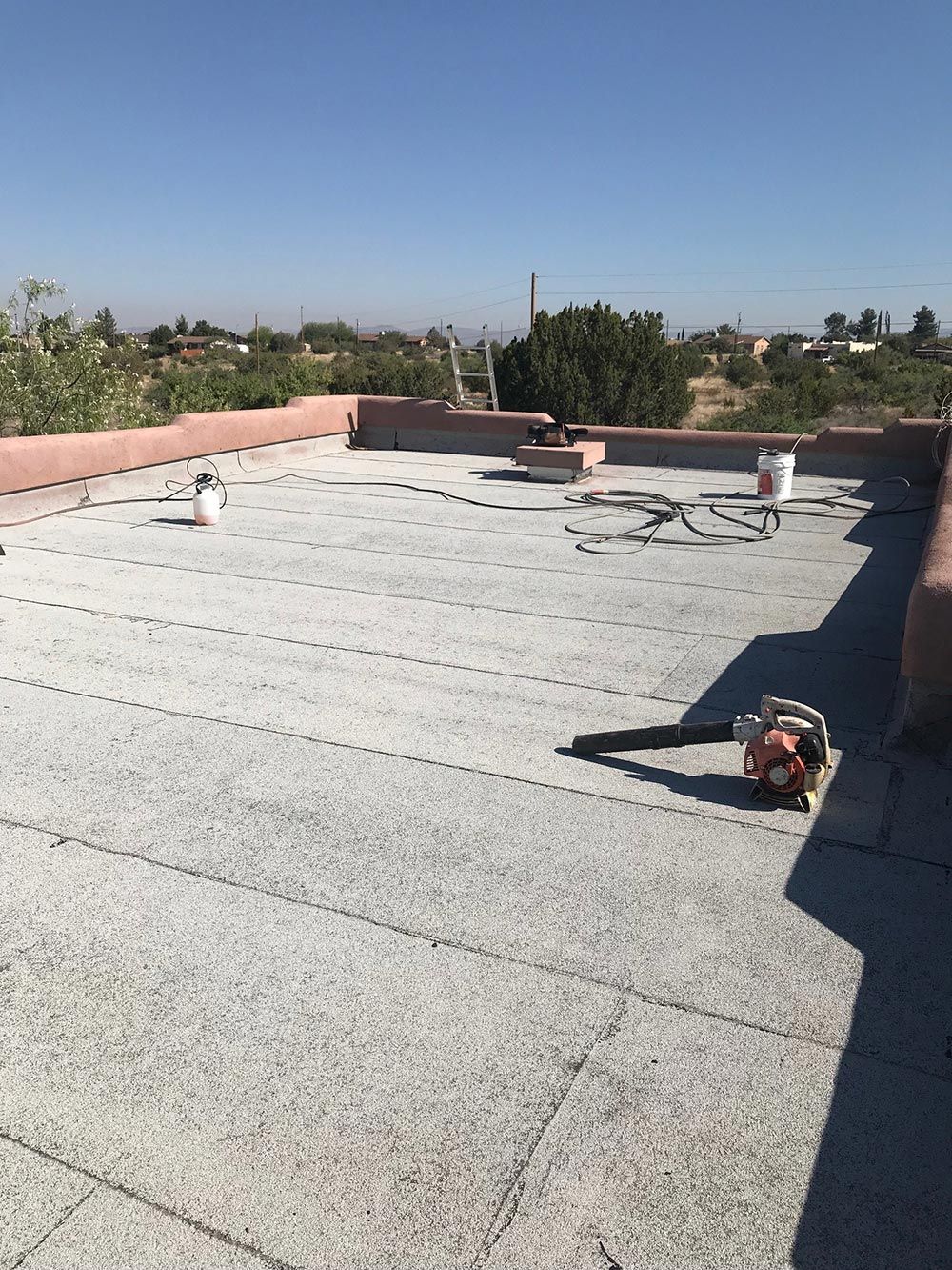 The roof of a building is being painted on a sunny day.