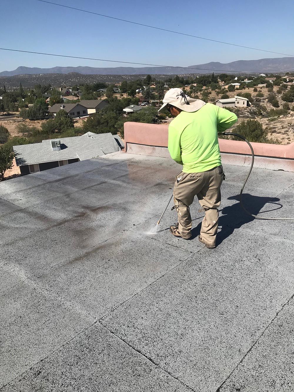 A man is spraying a roof with a sprayer.